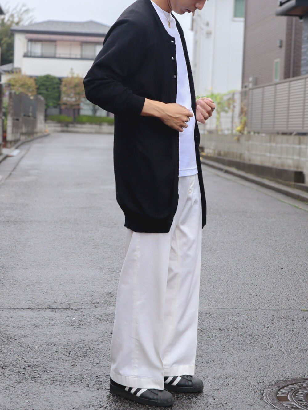 ホワイト系のチノパンツ、ブラック系のスニーカー、ブラック系のニット/セーターを着用したメンズの秋コーディネートの2枚目の写真