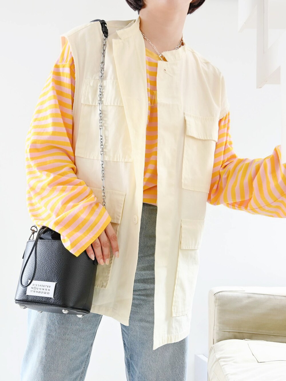 ピンク系のTシャツ/カットソー、ホワイト系のベスト、ブラック系のショルダーバッグを着用したレディースの夏コーディネートの2枚目の写真