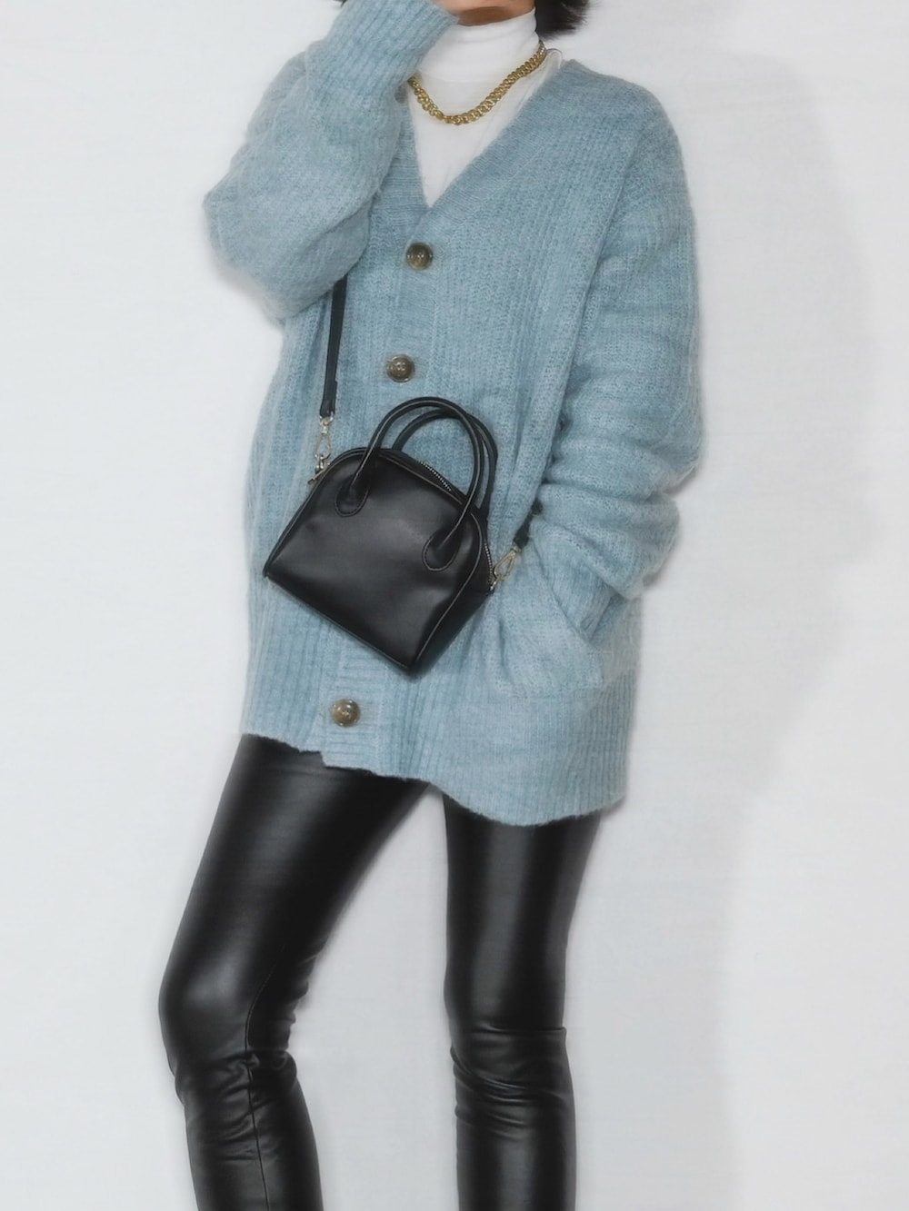 ブルー系のカーディガン/ボレロ、ブラック系のブーツ、ブラック系のボストンバッグを着用したレディースの冬コーディネートの2枚目の写真
