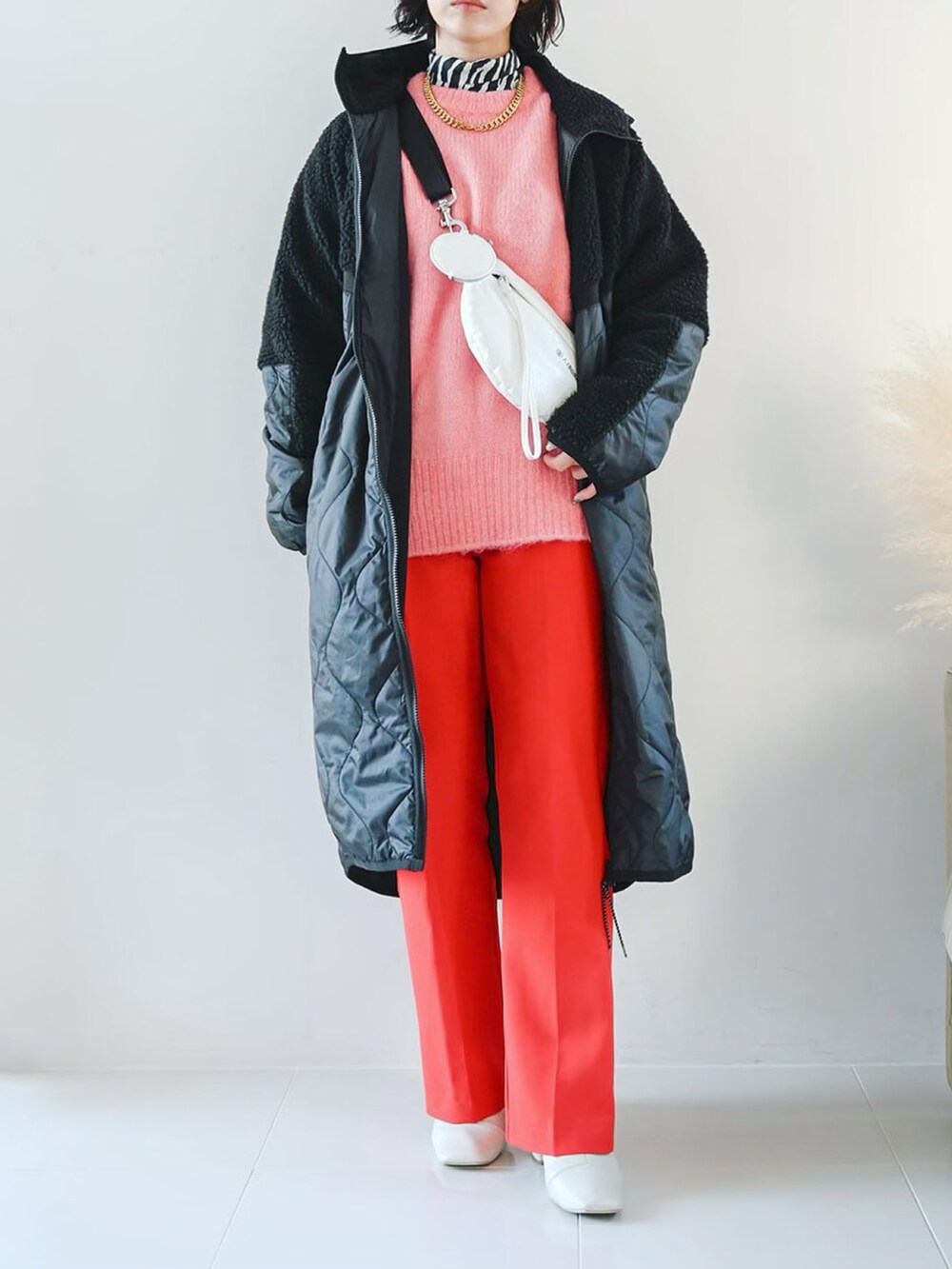 ピンク系のニット/セーター、レッド系のスラックス、ブラック系のTシャツ/カットソーを着用したレディースの冬コーディネートの3枚目の写真