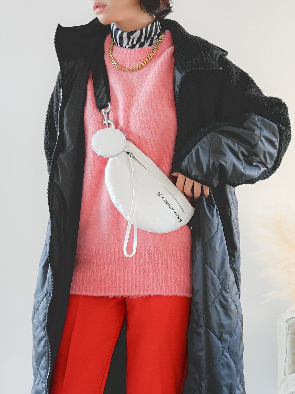 ピンク系のニット/セーター、レッド系のスラックス、ブラック系のTシャツ/カットソーを着用したレディースの冬コーディネートの2枚目の写真