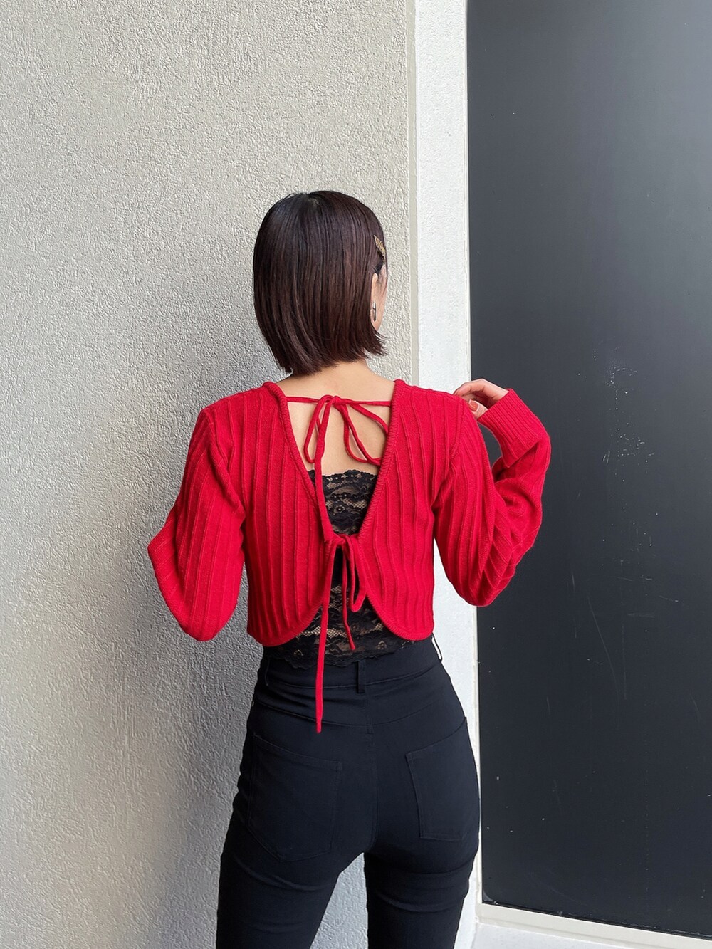 レッド系のニット/セーター、ブラック系のその他パンツ、ブラック系のブーツを着用したレディースの冬コーディネートの2枚目の写真