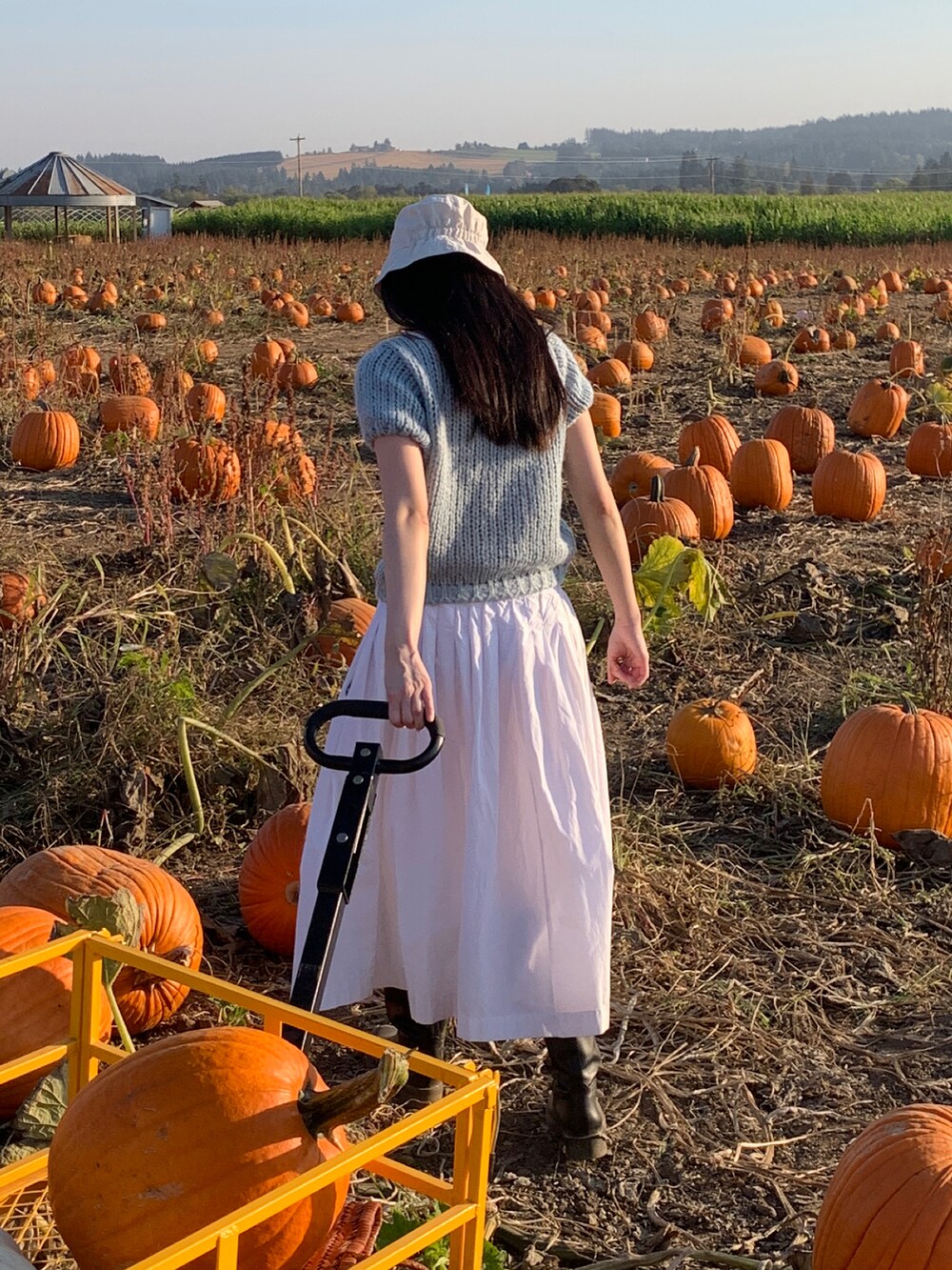 ブルー系のニット/セーター、ブラック系のシューズ、ホワイト系のスカートを着用したレディースの秋コーディネートの2枚目の写真