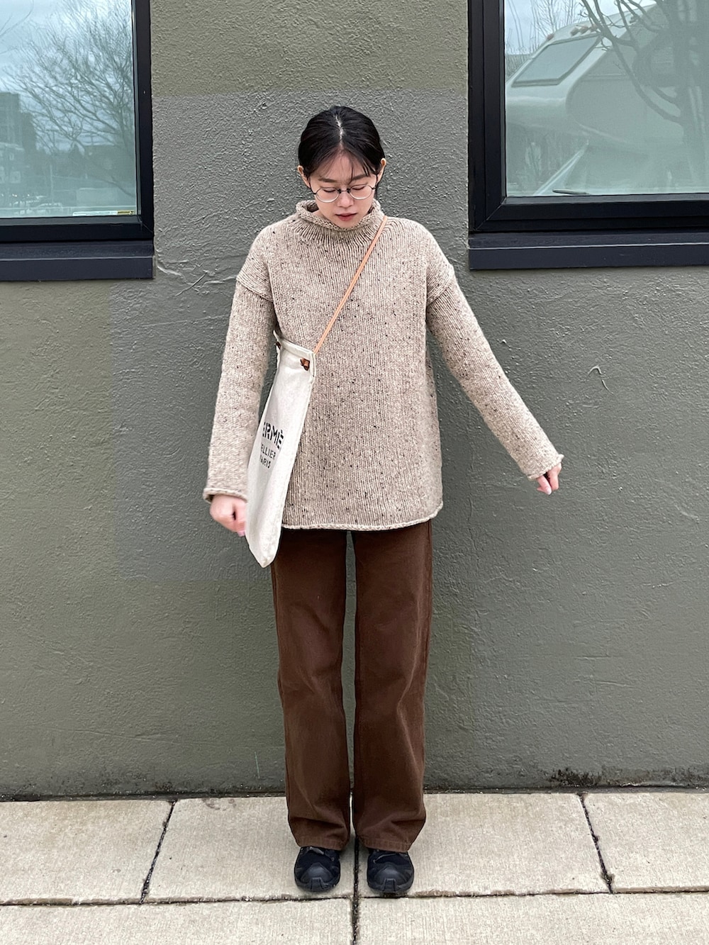 ベージュ系のニット/セーター、ホワイト系のバッグ、ブラック系のスニーカーを着用したレディースの冬コーディネートの2枚目の写真