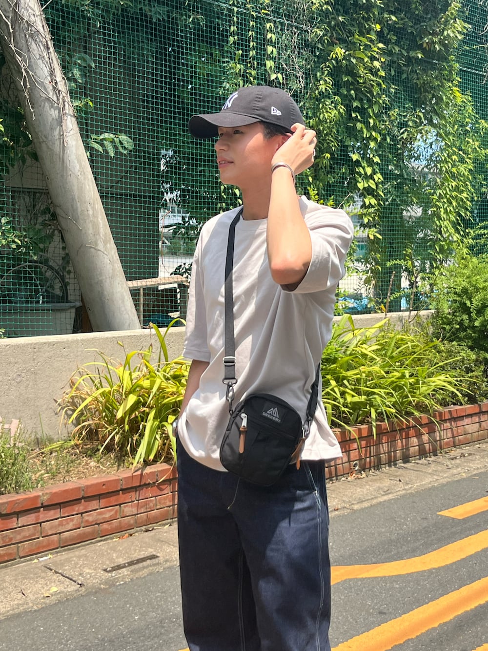 ホワイト系のTシャツ/カットソー、ブラック系のショルダーバッグ、ブルー系のデニムパンツを着用したメンズの夏コーディネートの2枚目の写真