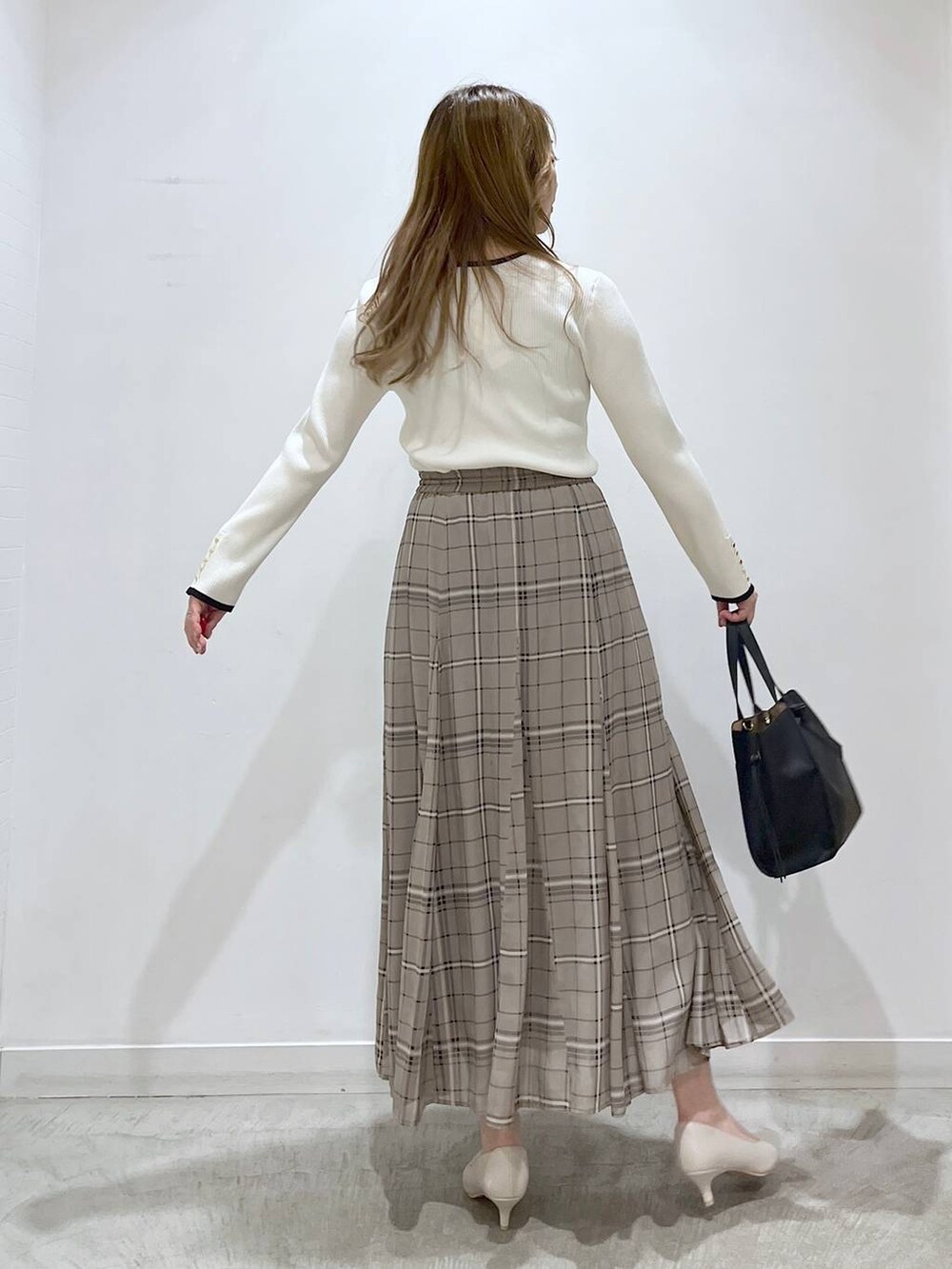 ホワイト系のTシャツ/カットソー、ホワイト系のパンプス、ブラック系のショルダーバッグを着用したレディースの春コーディネートの2枚目の写真