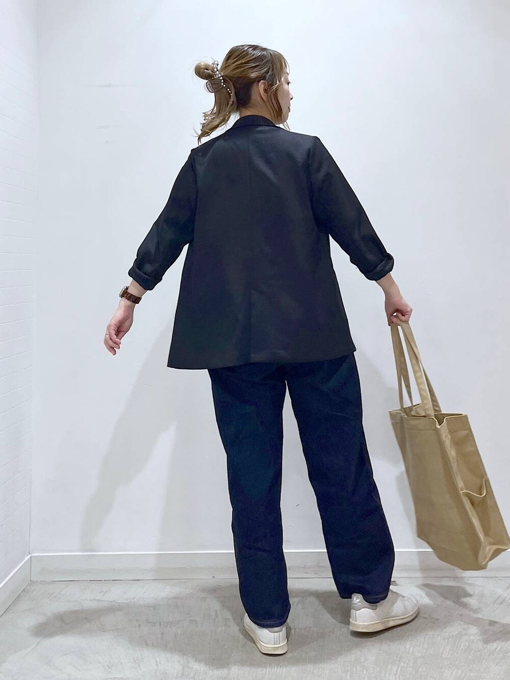 ブルー系のテーラードジャケット、ベージュ系のトートバッグ、ブルー系のデニムパンツを着用したレディースの春コーディネートの2枚目の写真