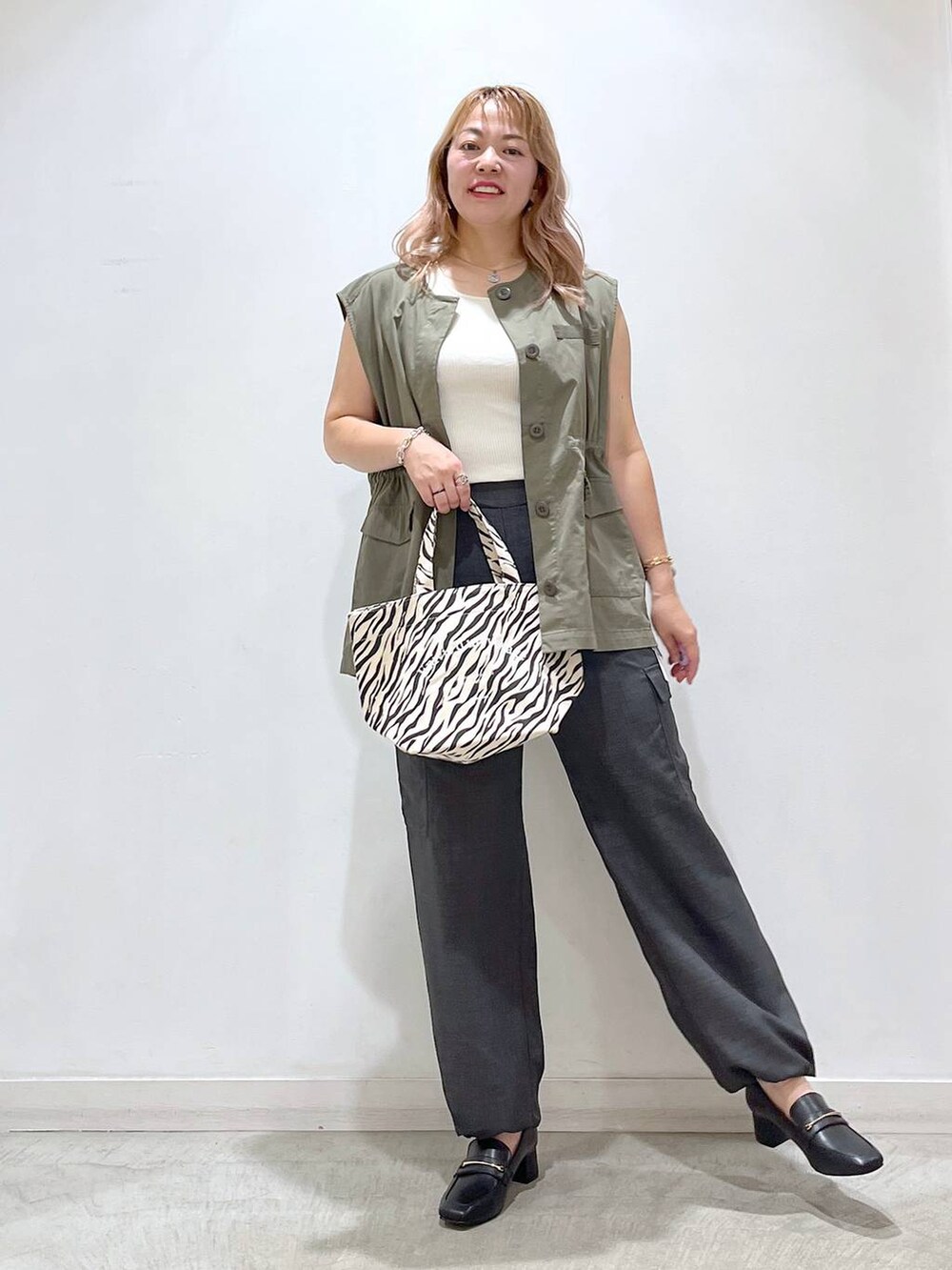 ホワイト系のタンクトップ、ブラック系のローファー、グレー系のカーゴパンツを着用したレディースの夏コーディネートの6枚目の写真