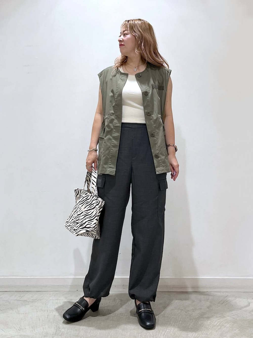 ホワイト系のタンクトップ、ブラック系のローファー、グレー系のカーゴパンツを着用したレディースの夏コーディネートの3枚目の写真