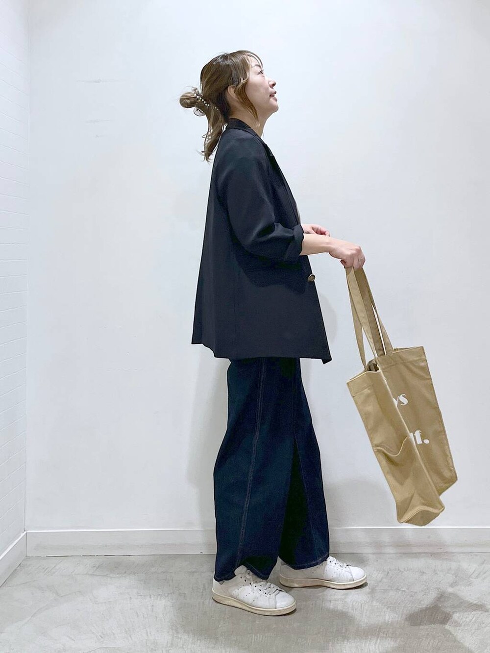 ブルー系のテーラードジャケット、ベージュ系のトートバッグ、ブルー系のデニムパンツを着用したレディースの春コーディネートの4枚目の写真
