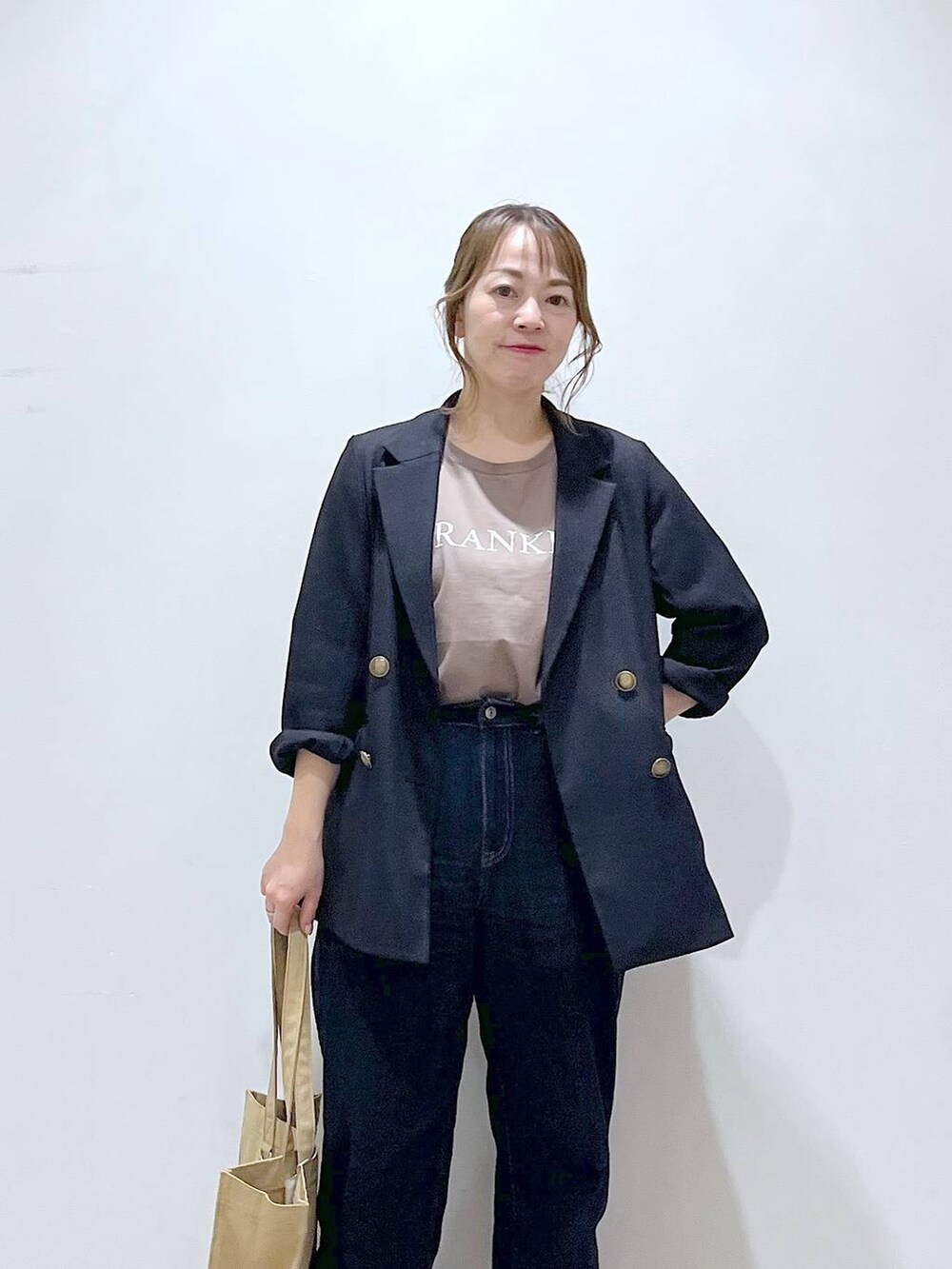 ブルー系のテーラードジャケット、ベージュ系のトートバッグ、ブルー系のデニムパンツを着用したレディースの春コーディネートの6枚目の写真