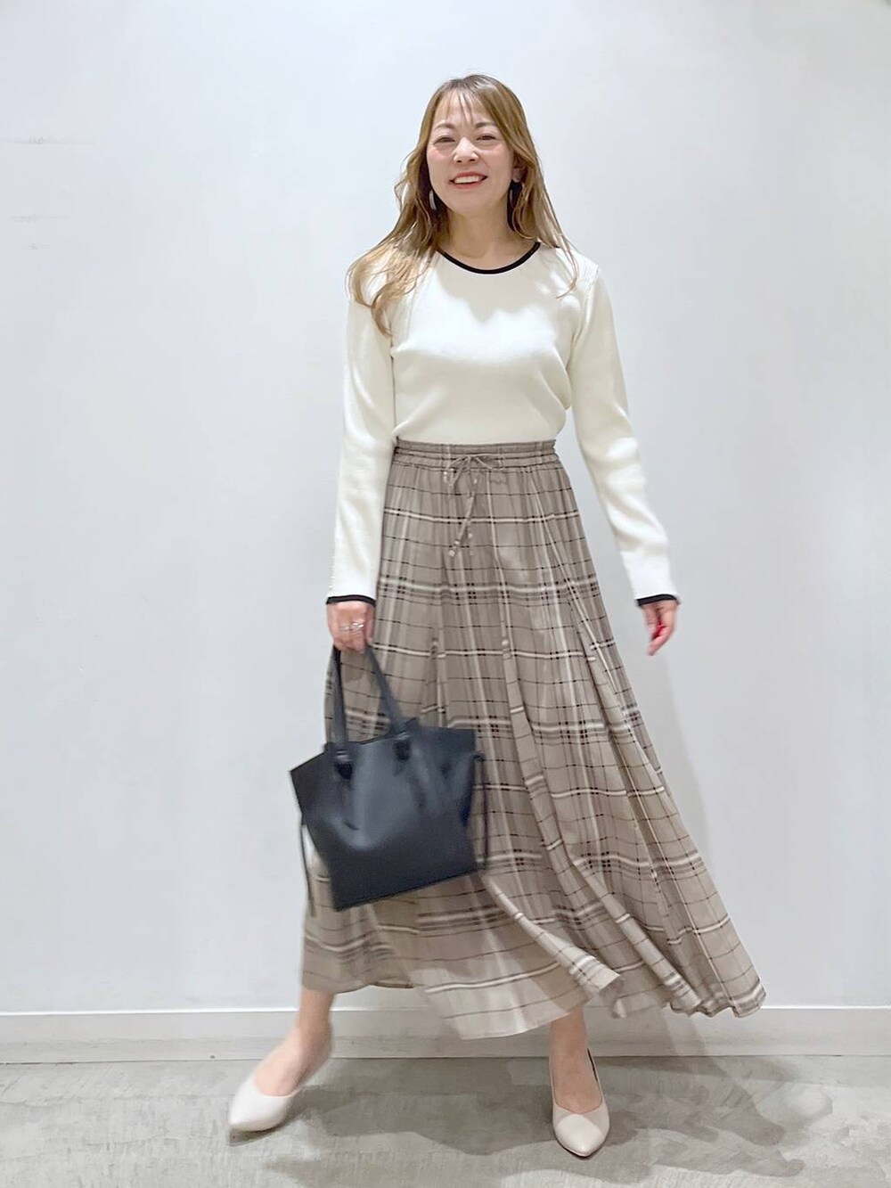 ホワイト系のTシャツ/カットソー、ホワイト系のパンプス、ブラック系のショルダーバッグを着用したレディースの春コーディネートの3枚目の写真