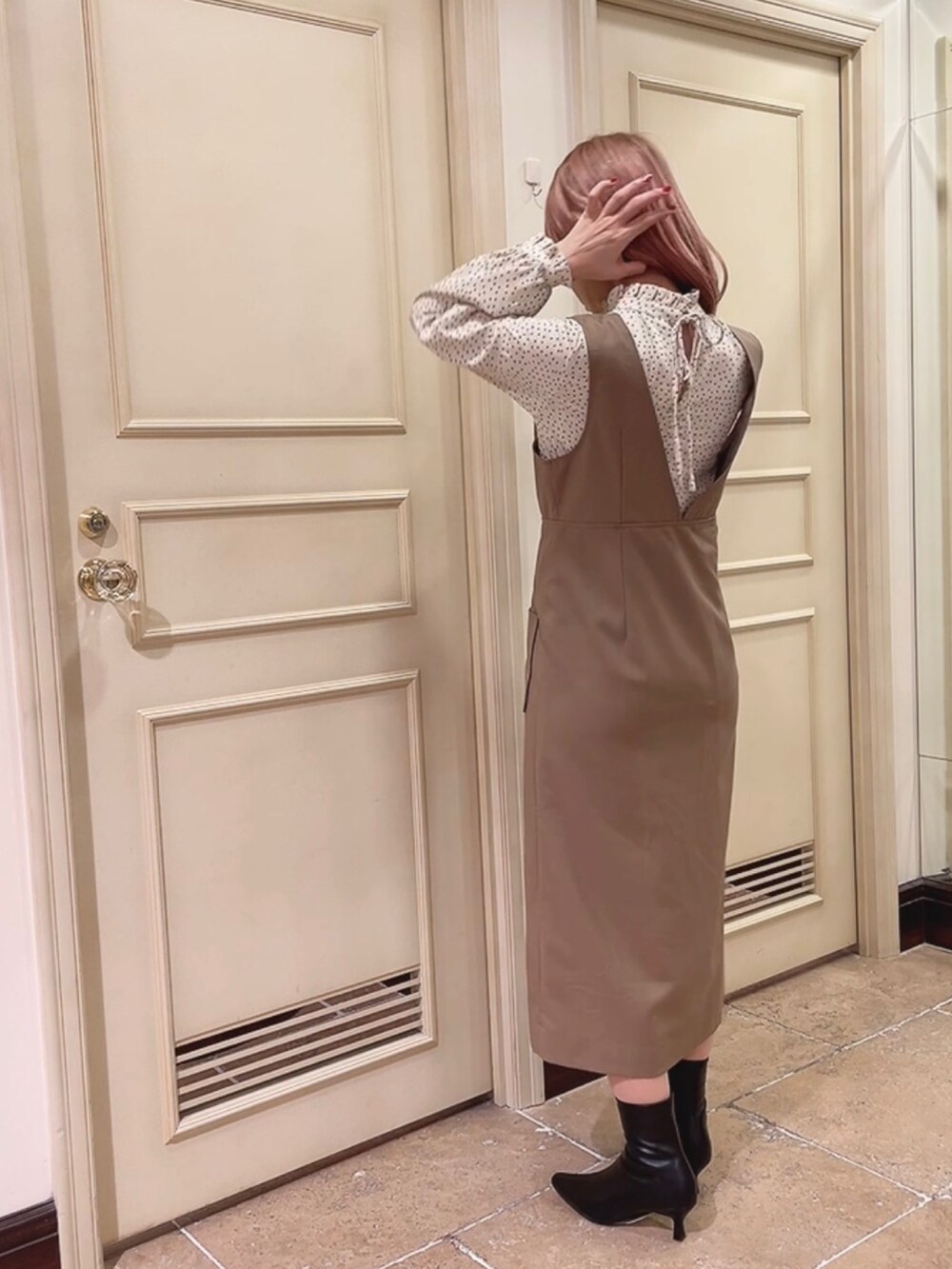 ブラック系のブーツ、ブラウン系のジャンパースカート、ベージュ系のシャツ/ブラウスを着用したレディースの冬コーディネートの2枚目の写真