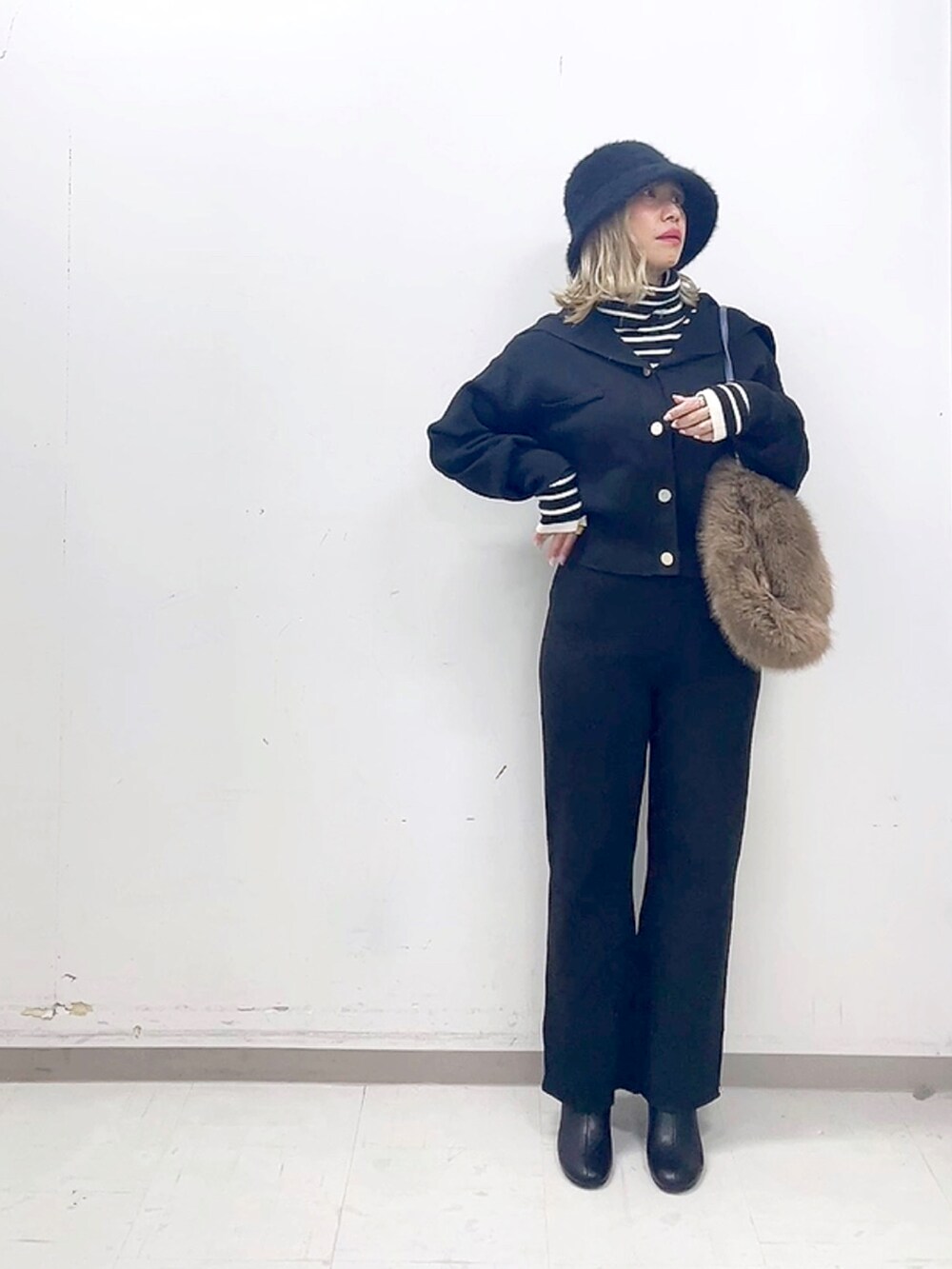 ブラック系のブーツ、ブラック系のその他パンツ、ブルー系のハンドバッグを着用したレディースの秋コーディネートの4枚目の写真