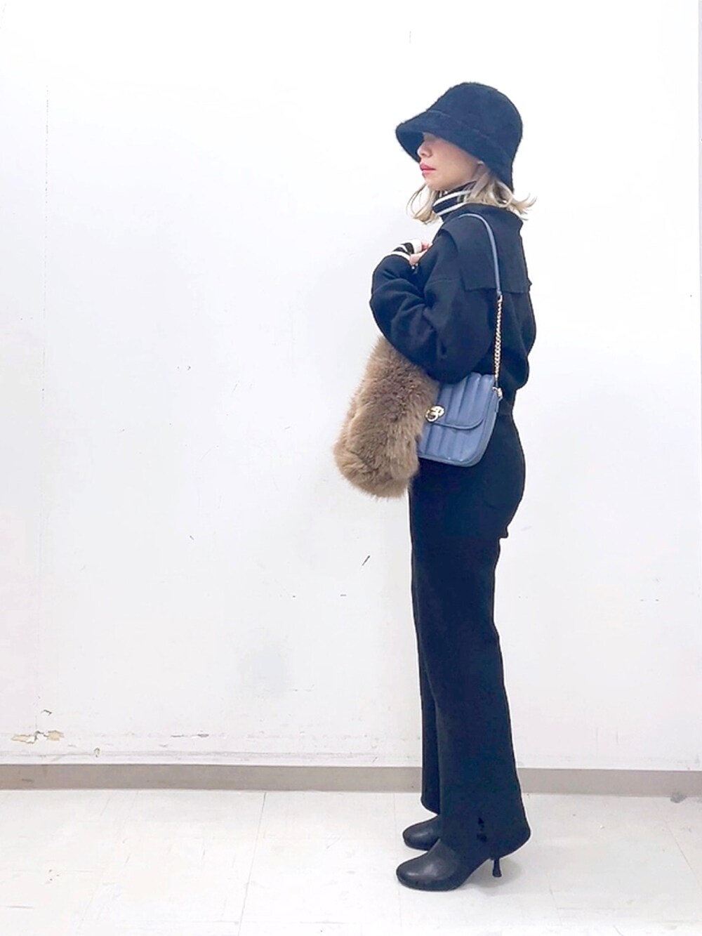 ブラック系のブーツ、ブラック系のその他パンツ、ブルー系のハンドバッグを着用したレディースの秋コーディネートの3枚目の写真