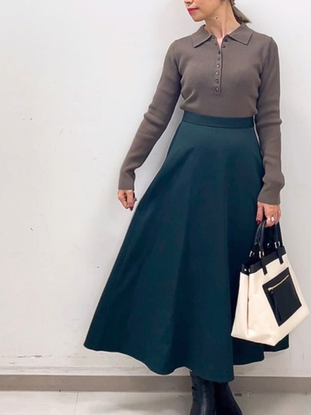 ホワイト系のハンドバッグ、ブラウン系のニット/セーター、グリーン系のスカートを着用したレディースの秋コーディネートの3枚目の写真