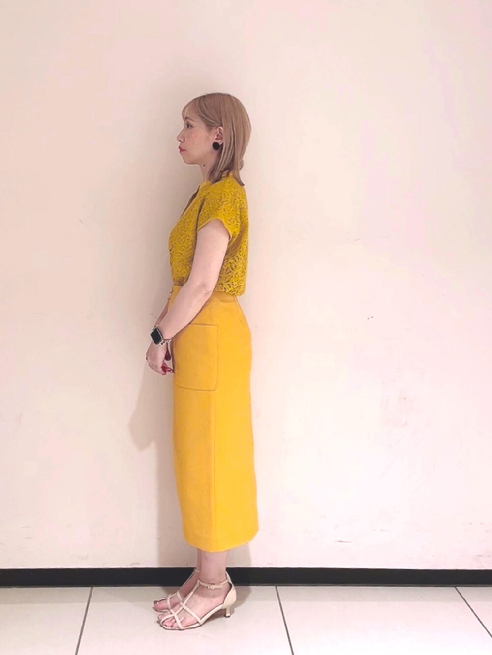 イエロー系のシャツ/ブラウス、イエロー系のスカート、ホワイト系のサンダルを着用したレディースの春コーディネートの2枚目の写真