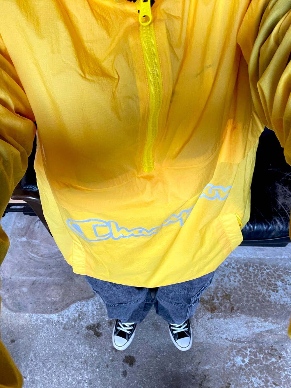 イエロー系のナイロンジャケット、グレー系のデニムパンツ、ブラック系のスニーカーを着用したレディースの冬コーディネートの2枚目の写真