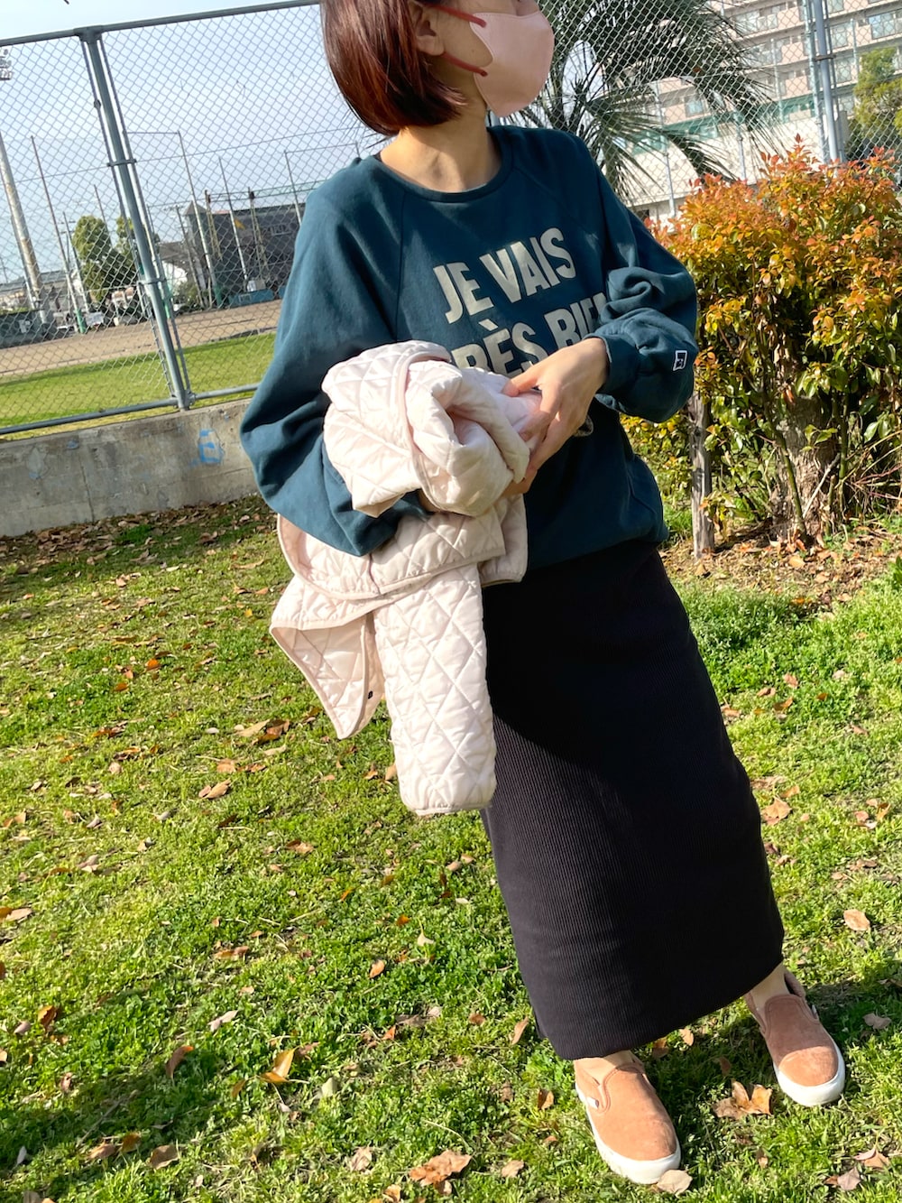 グリーン系のスウェット、ブラック系のスカート、ピンク系のスニーカーを着用したレディースの春コーディネートの3枚目の写真