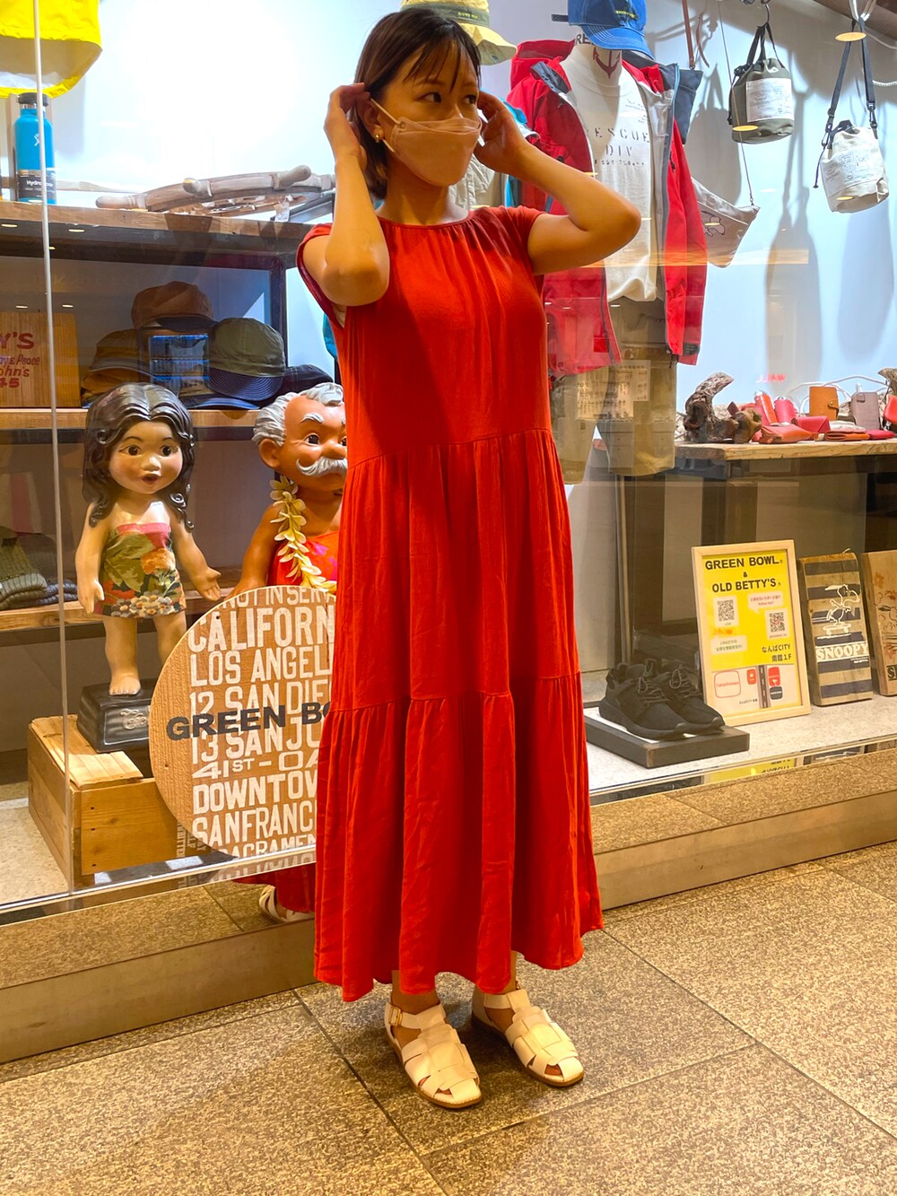 オレンジ系のワンピース、ホワイト系のサンダル、ゴールド系のピアス（両耳用）を着用したレディースの夏コーディネートの2枚目の写真