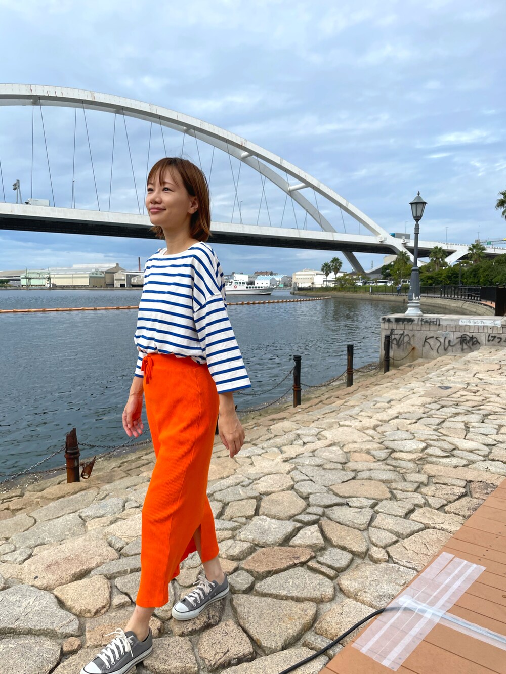 オレンジ系のスカート、ブルー系のTシャツ/カットソーを着用したレディースの秋コーディネートの2枚目の写真