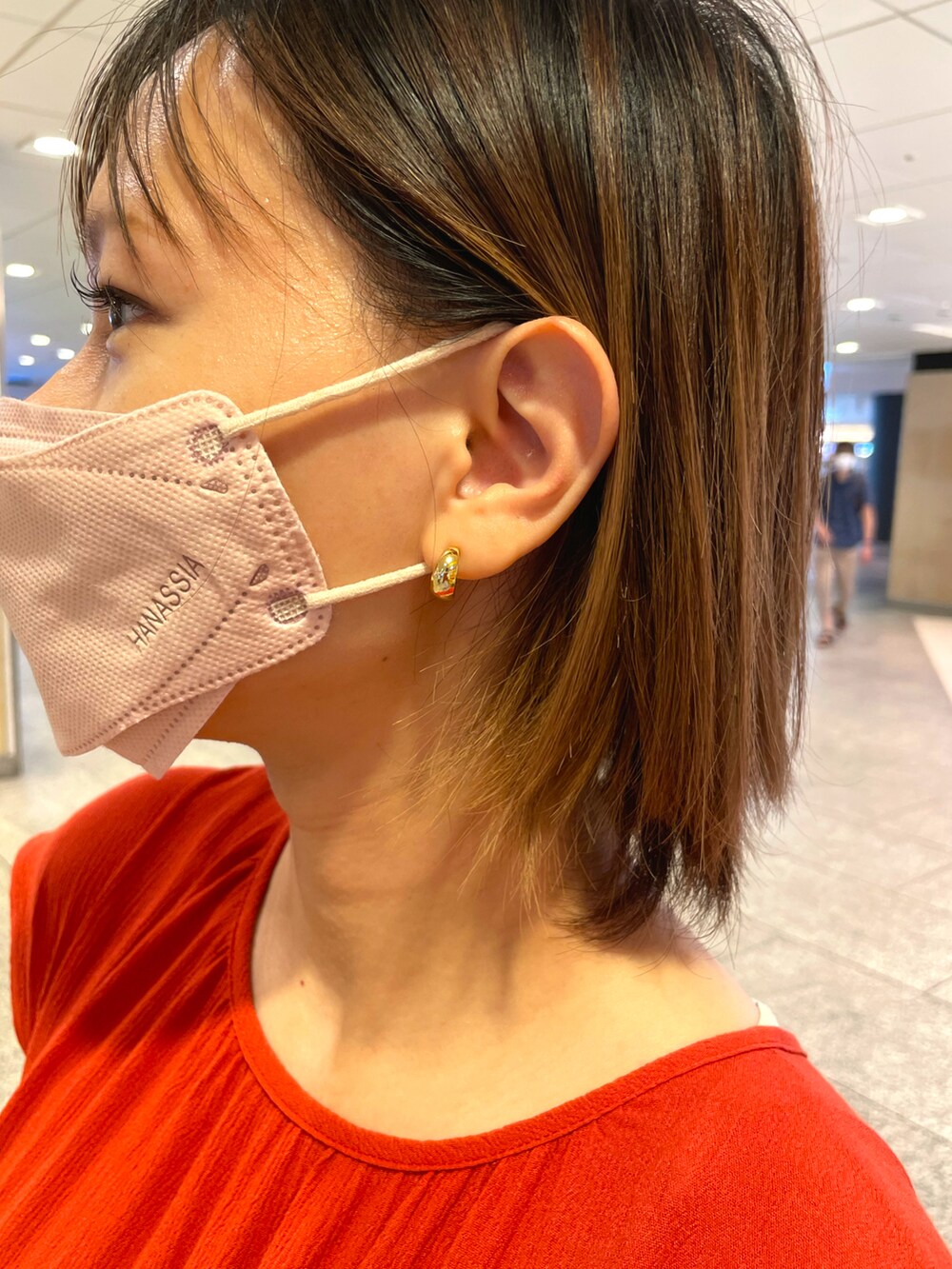 オレンジ系のワンピース、ホワイト系のサンダル、ゴールド系のピアス（両耳用）を着用したレディースの夏コーディネートの3枚目の写真