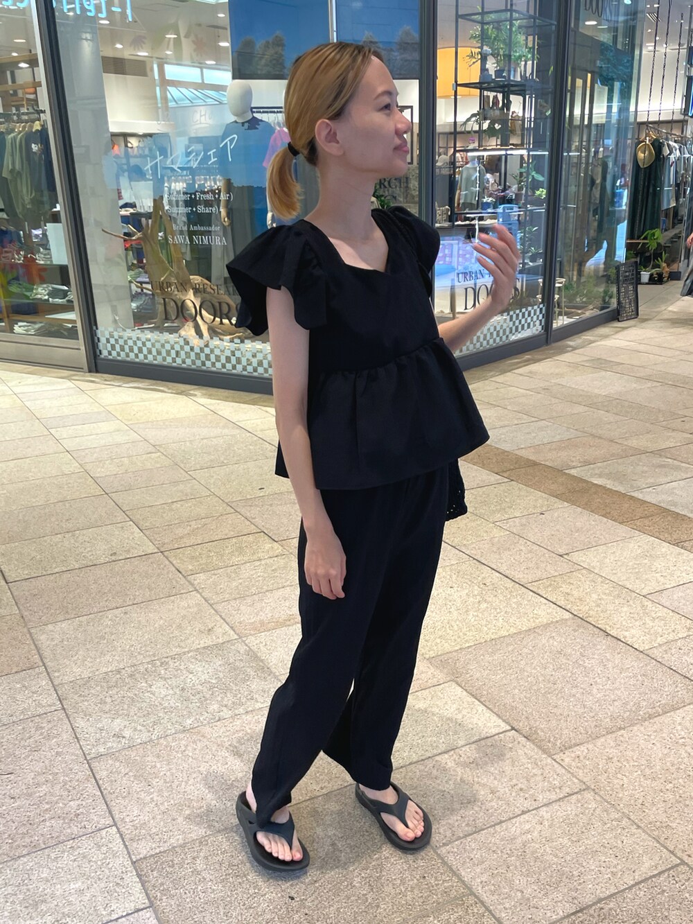 ブラック系のセットアップ、ブラック系のトートバッグ、ブラック系のサンダルを着用したレディースの夏コーディネートの2枚目の写真