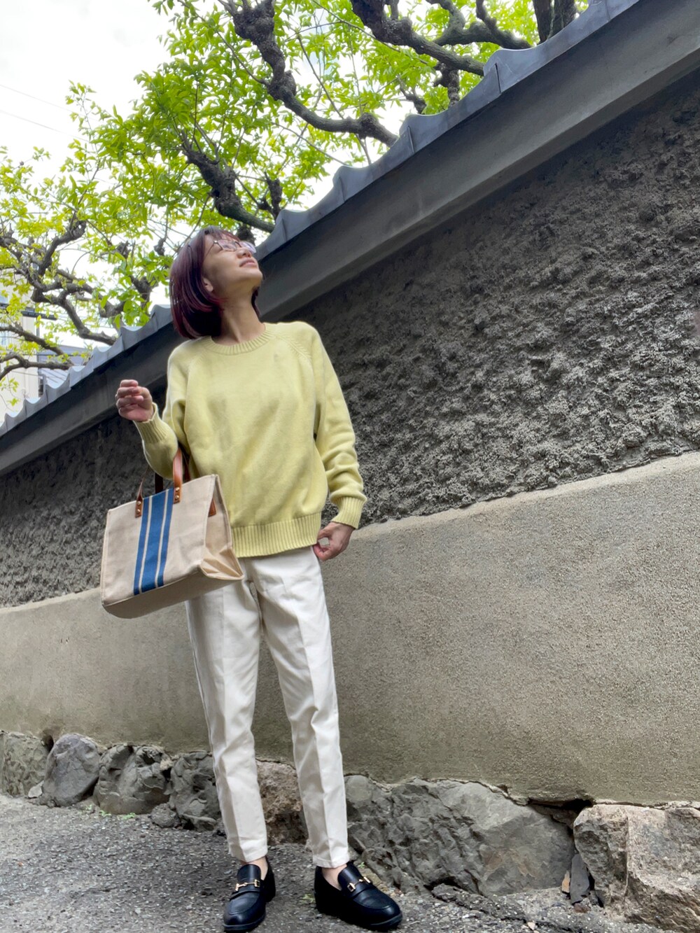 ホワイト系のデニムパンツ、ブラック系のローファー、ブルー系のショルダーバッグを着用したレディースの春コーディネートの2枚目の写真