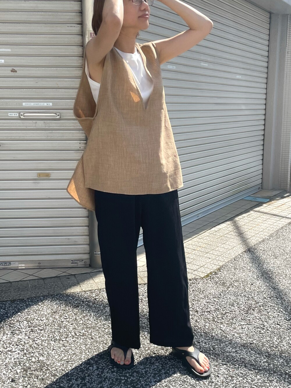 ブラック系のセットアップ、ブラック系のサンダル、ベージュ系のベストを着用したレディースの夏コーディネートの3枚目の写真