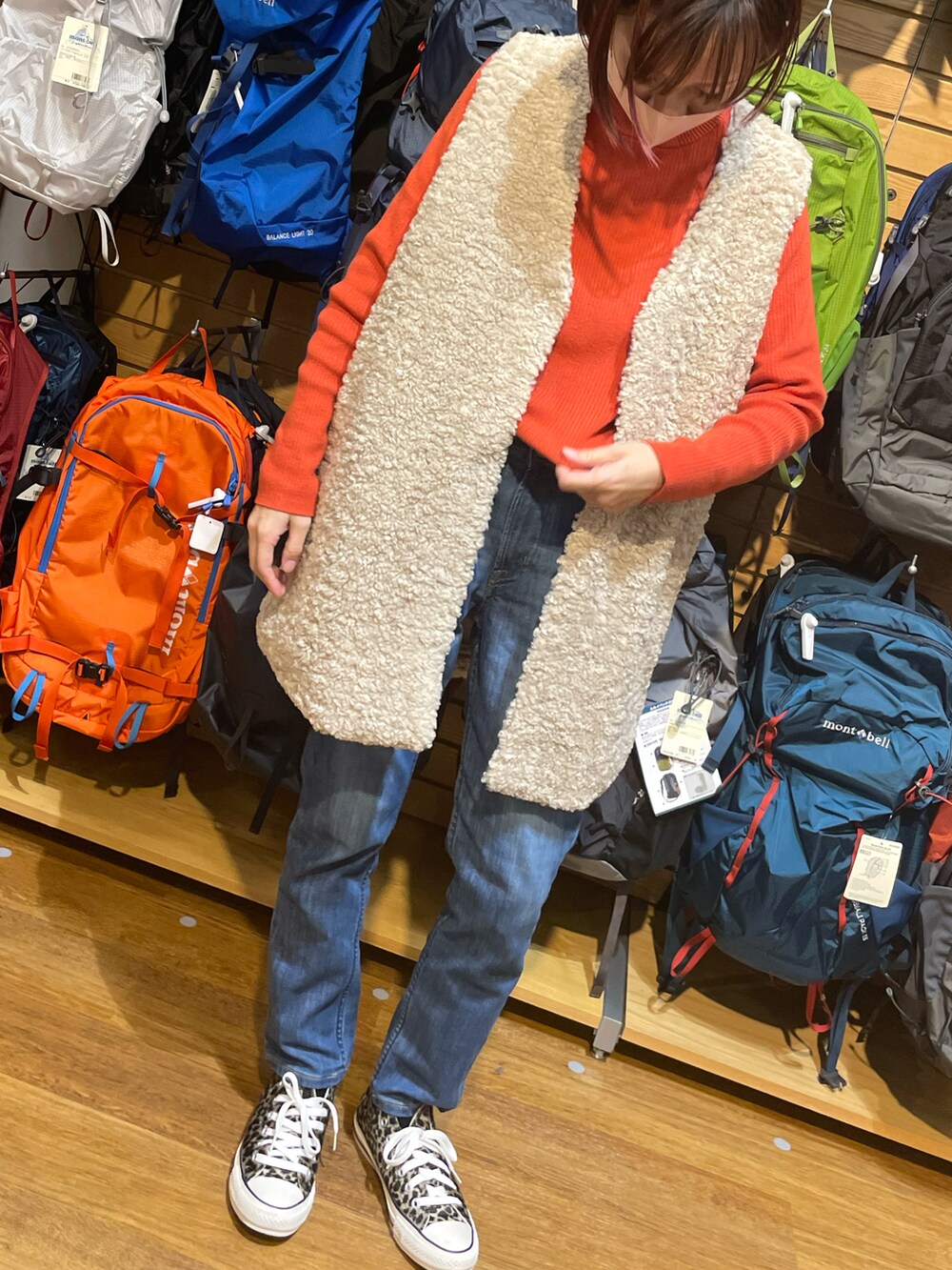 オレンジ系のニット/セーター、ブルー系のデニムパンツ、ベージュ系のスニーカーを着用したレディースの冬コーディネートの2枚目の写真