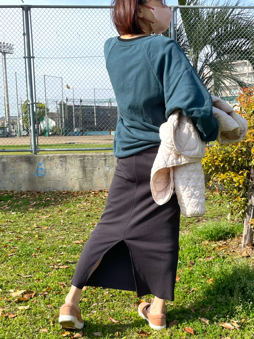 グリーン系のスウェット、ブラック系のスカート、ピンク系のスニーカーを着用したレディースの春コーディネートの4枚目の写真