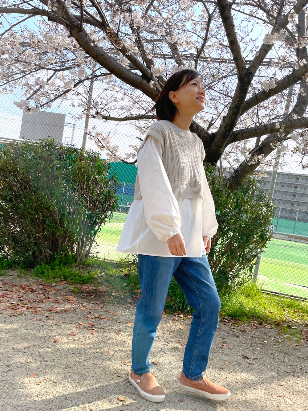 ブルー系のデニムパンツ、ベージュ系のシャツ/ブラウス、グリーン系のマウンテンパーカーを着用したレディースの春コーディネートの2枚目の写真