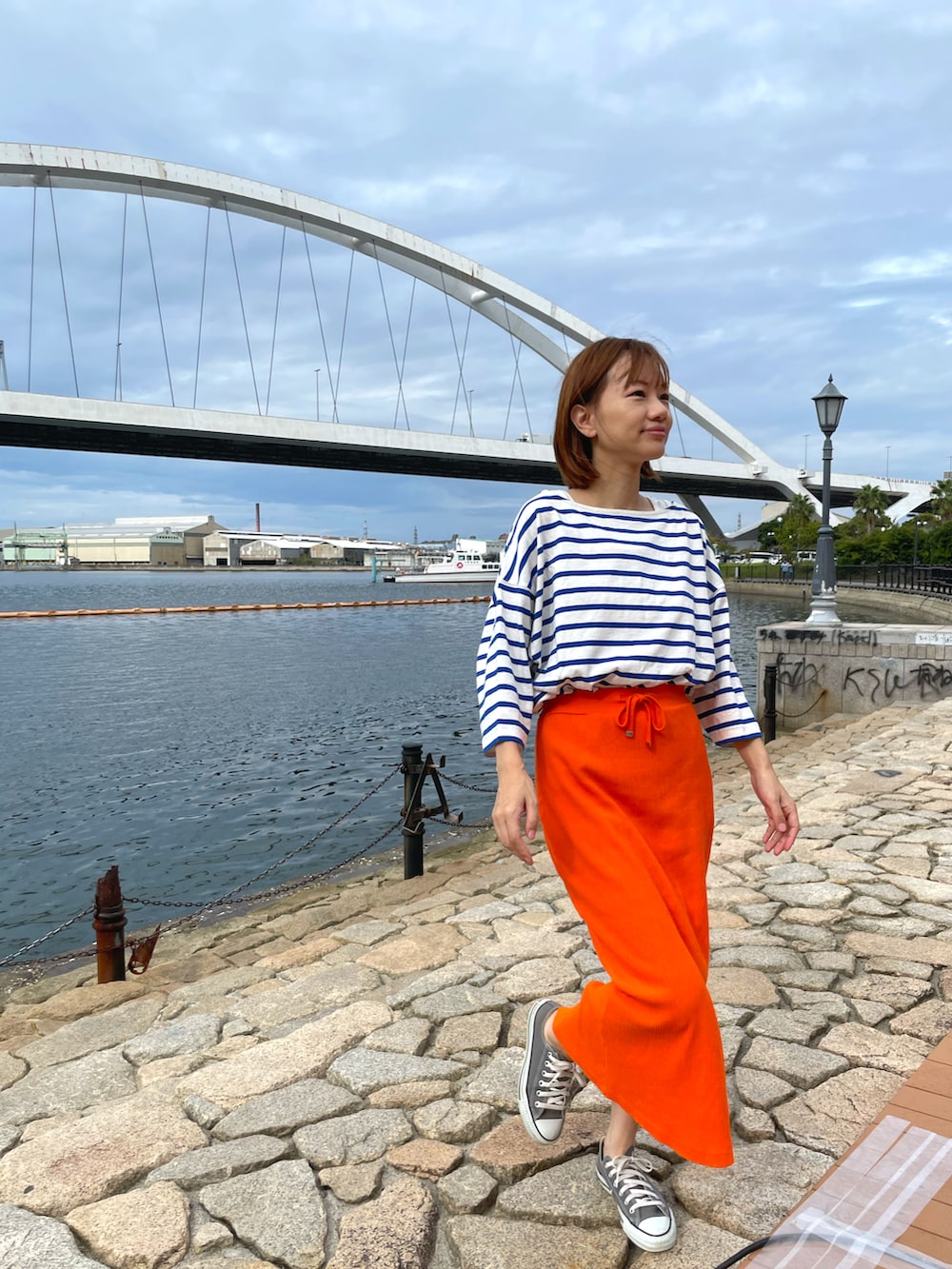 オレンジ系のスカート、ブルー系のTシャツ/カットソーを着用したレディースの秋コーディネートの3枚目の写真