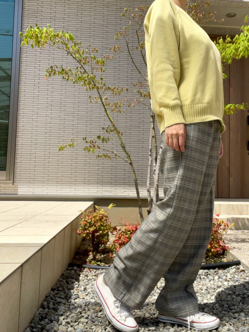 グレー系のその他パンツ、イエロー系のニット/セーター、ホワイト系のスニーカーを着用したレディースの春コーディネートの2枚目の写真