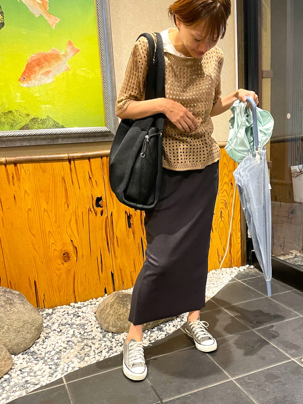 ブラウン系のTシャツ/カットソー、ブラック系のスカート、グレー系のスニーカーを着用したレディースの夏コーディネートの2枚目の写真