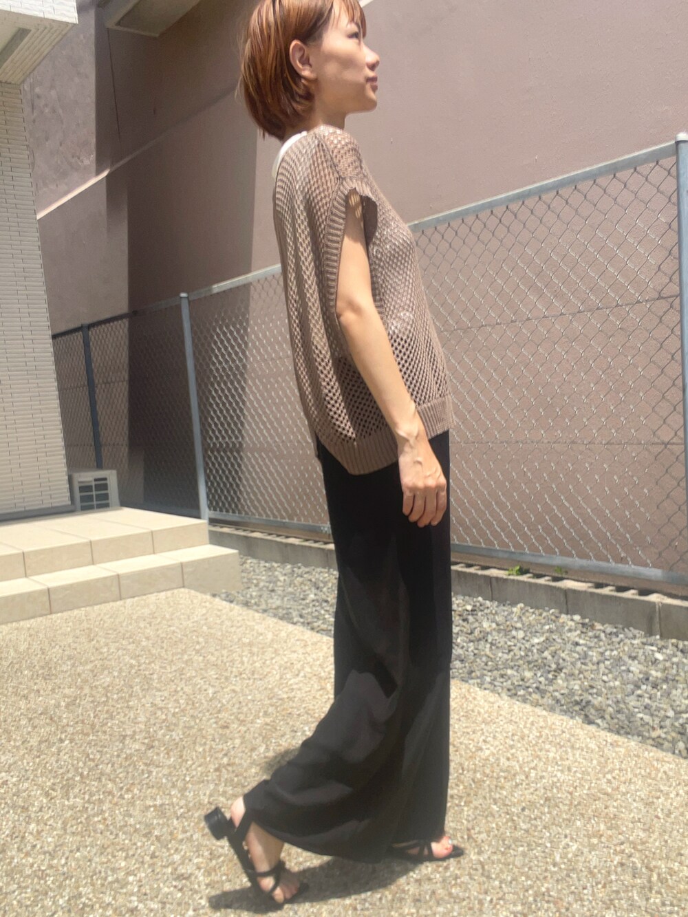 ホワイト系のTシャツ/カットソー、ブラウン系のベスト、ブラック系のサンダルを着用したレディースの夏コーディネートの3枚目の写真