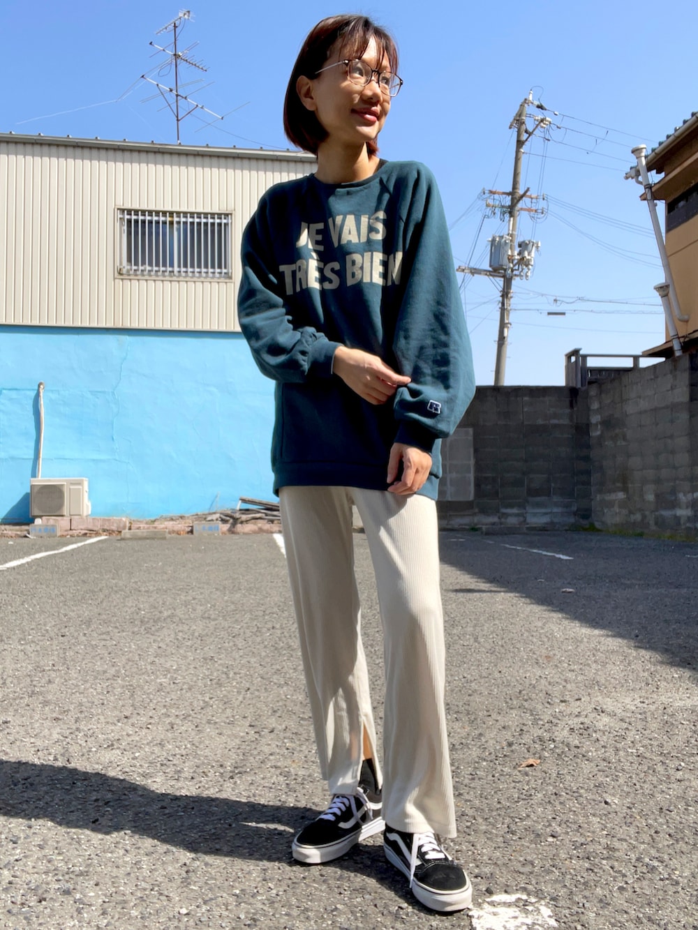 グリーン系のスウェット、ホワイト系のパンツ、ブラック系のスニーカーを着用したレディースの春コーディネートの2枚目の写真