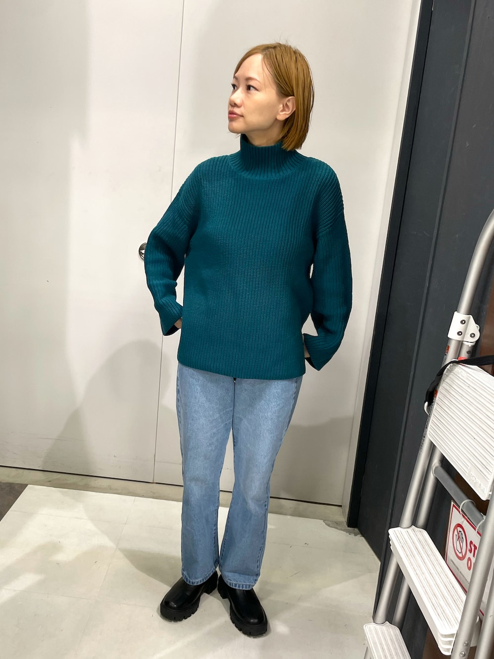 ブラック系のブーツ、グリーン系のニット/セーター、ブルー系のデニムパンツを着用したレディースの冬コーディネートの2枚目の写真