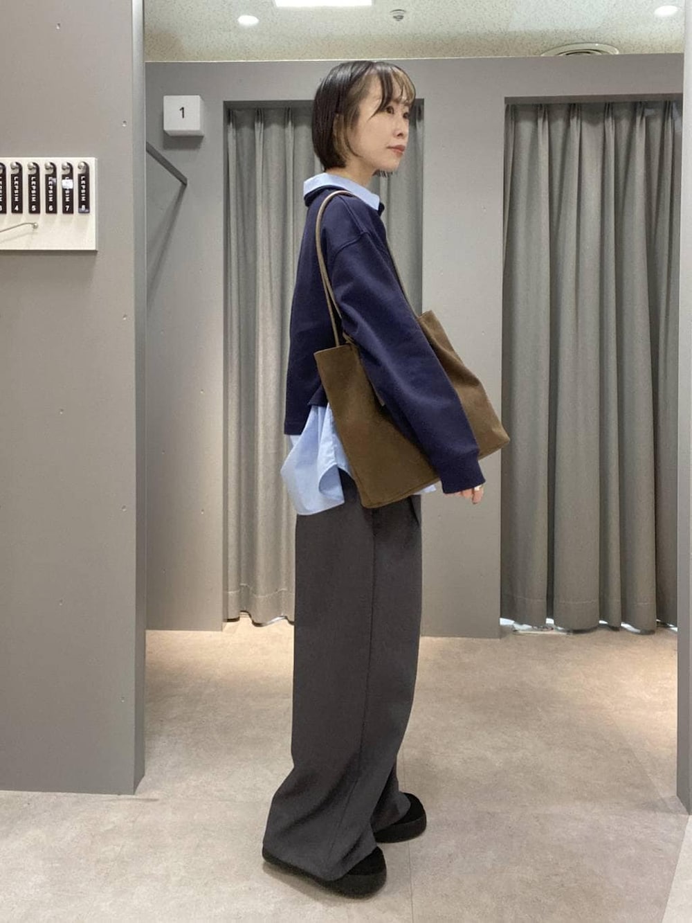 ブラウン系のトートバッグ、ブルー系のTシャツ/カットソー、グレー系のその他パンツを着用したレディースの冬コーディネートの2枚目の写真