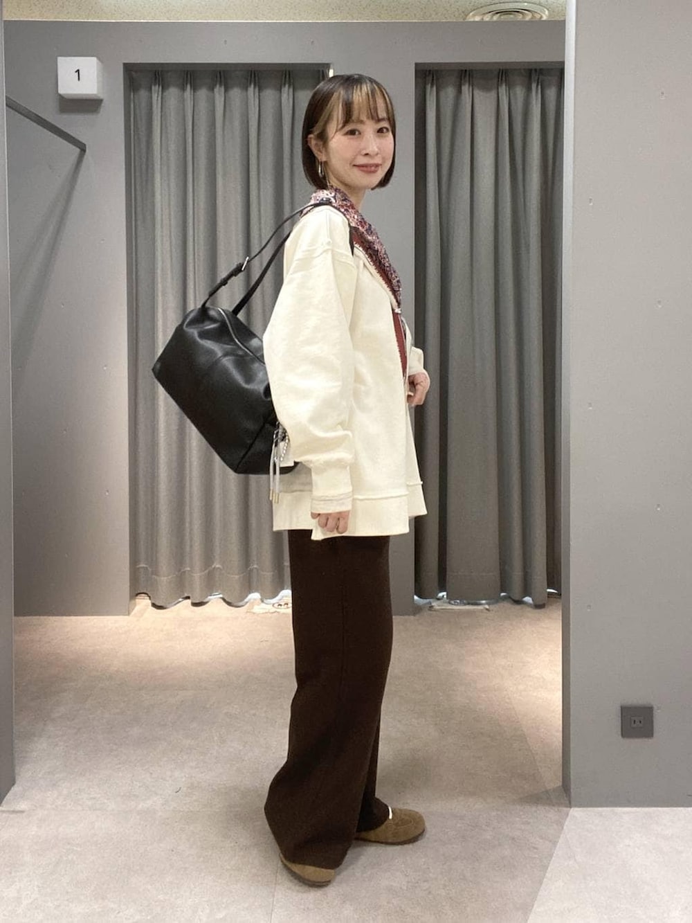 ブラウン系のスニーカー、ブラック系のボストンバッグ、ホワイト系のスウェットを着用したレディースの春コーディネートの2枚目の写真