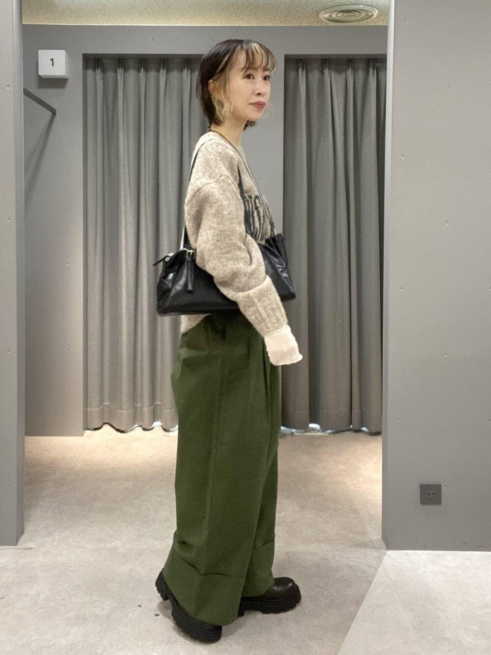 ブラック系のボストンバッグ、グリーン系のその他パンツ、ベージュ系のニット/セーターを着用したレディースの秋コーディネートの2枚目の写真