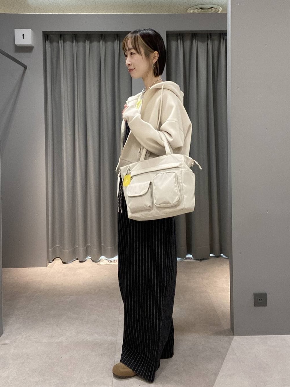 イエロー系のTシャツ/カットソー、ブラック系のサロペット/オーバーオール、ホワイト系のトートバッグを着用したレディースの冬コーディネートの2枚目の写真