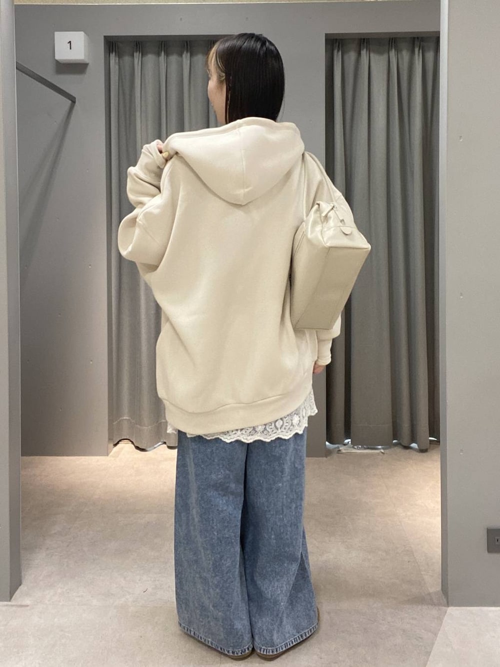 ホワイト系のパーカー、ブルー系のデニムパンツ、ホワイト系のボストンバッグを着用したレディースの春コーディネートの3枚目の写真