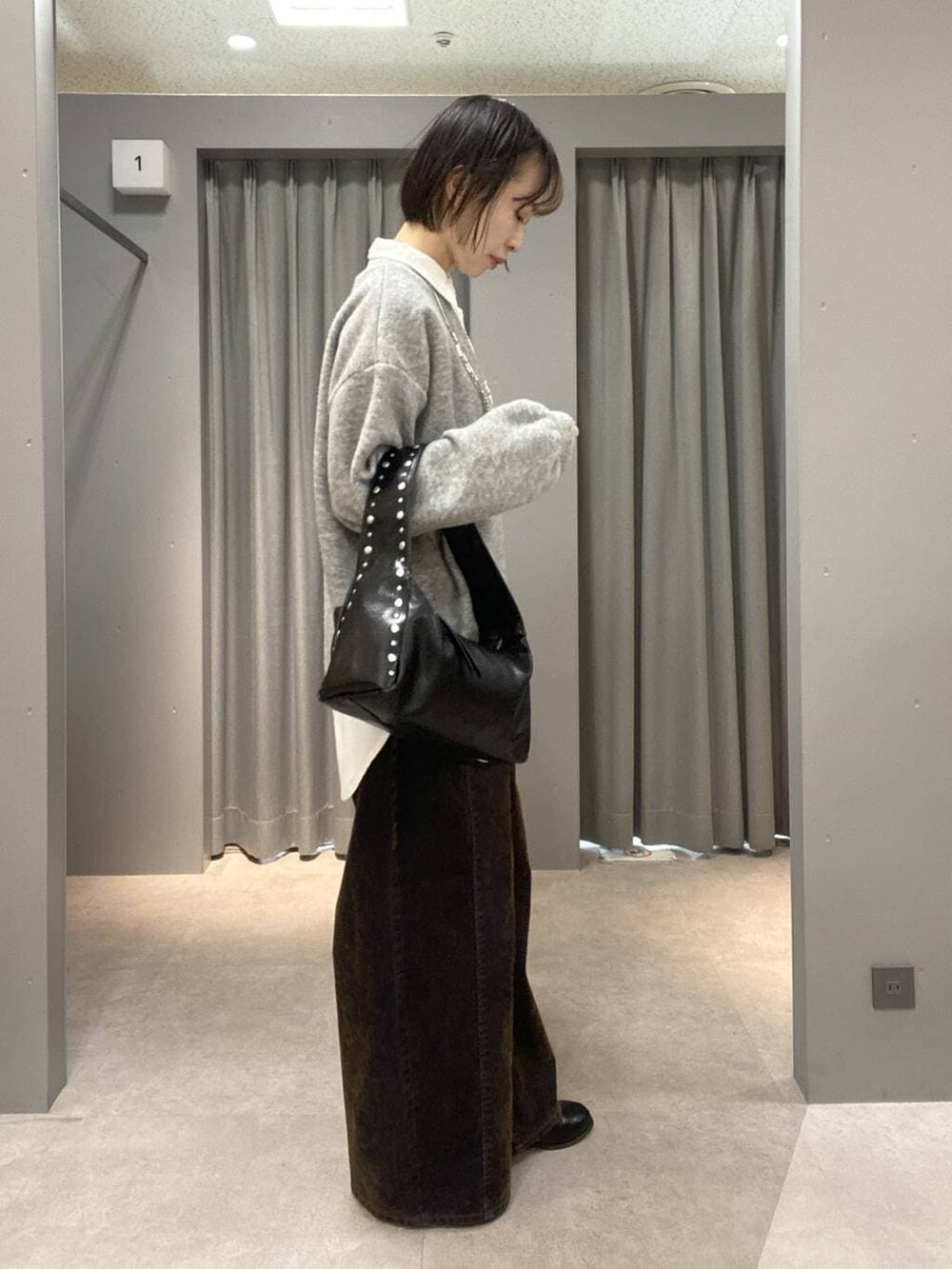 ブラック系のブーツ、ブラック系のハンドバッグ、グレー系のTシャツ/カットソーを着用したレディースの冬コーディネートの2枚目の写真