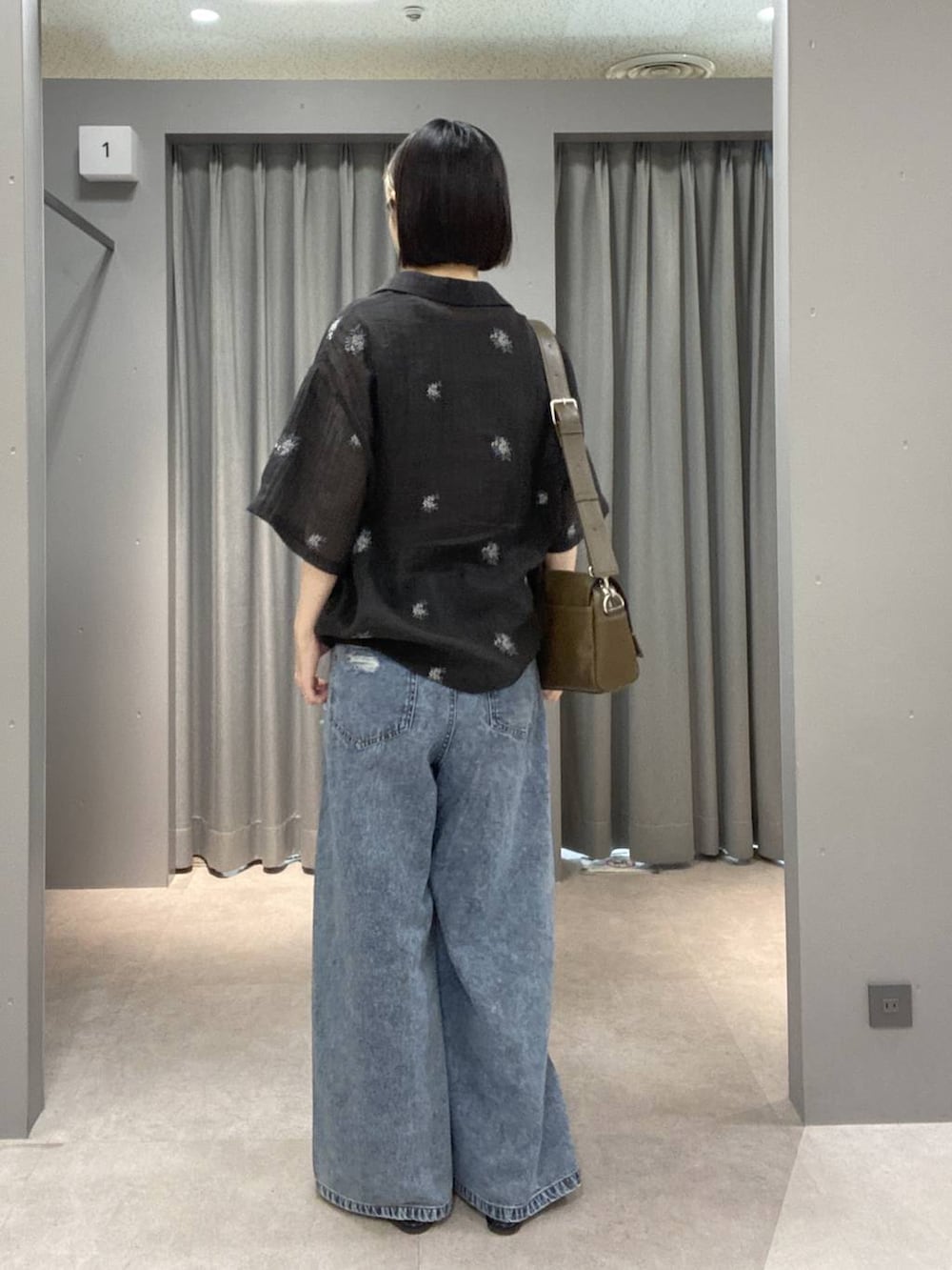 ブラウン系のショルダーバッグ、ブルー系のデニムパンツ、ブラック系のパンプスを着用したレディースの春コーディネートの3枚目の写真