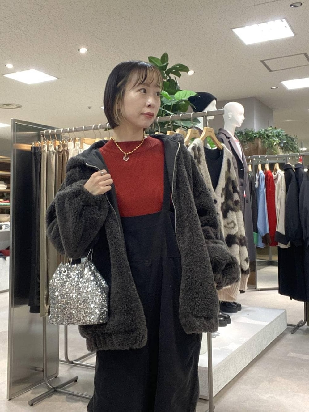 レッド系のニット/セーター、シルバー系のショルダーバッグ、グレー系のサロペット/オーバーオールを着用したレディースの冬コーディネートの4枚目の写真