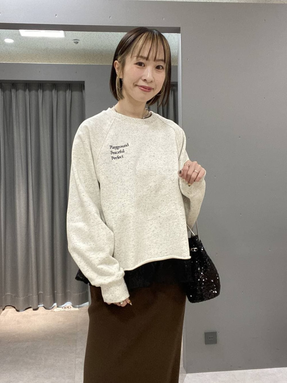 ブラウン系のスカート、ブラック系のショルダーバッグ、グレー系のスウェットを着用したレディースの冬コーディネートの4枚目の写真