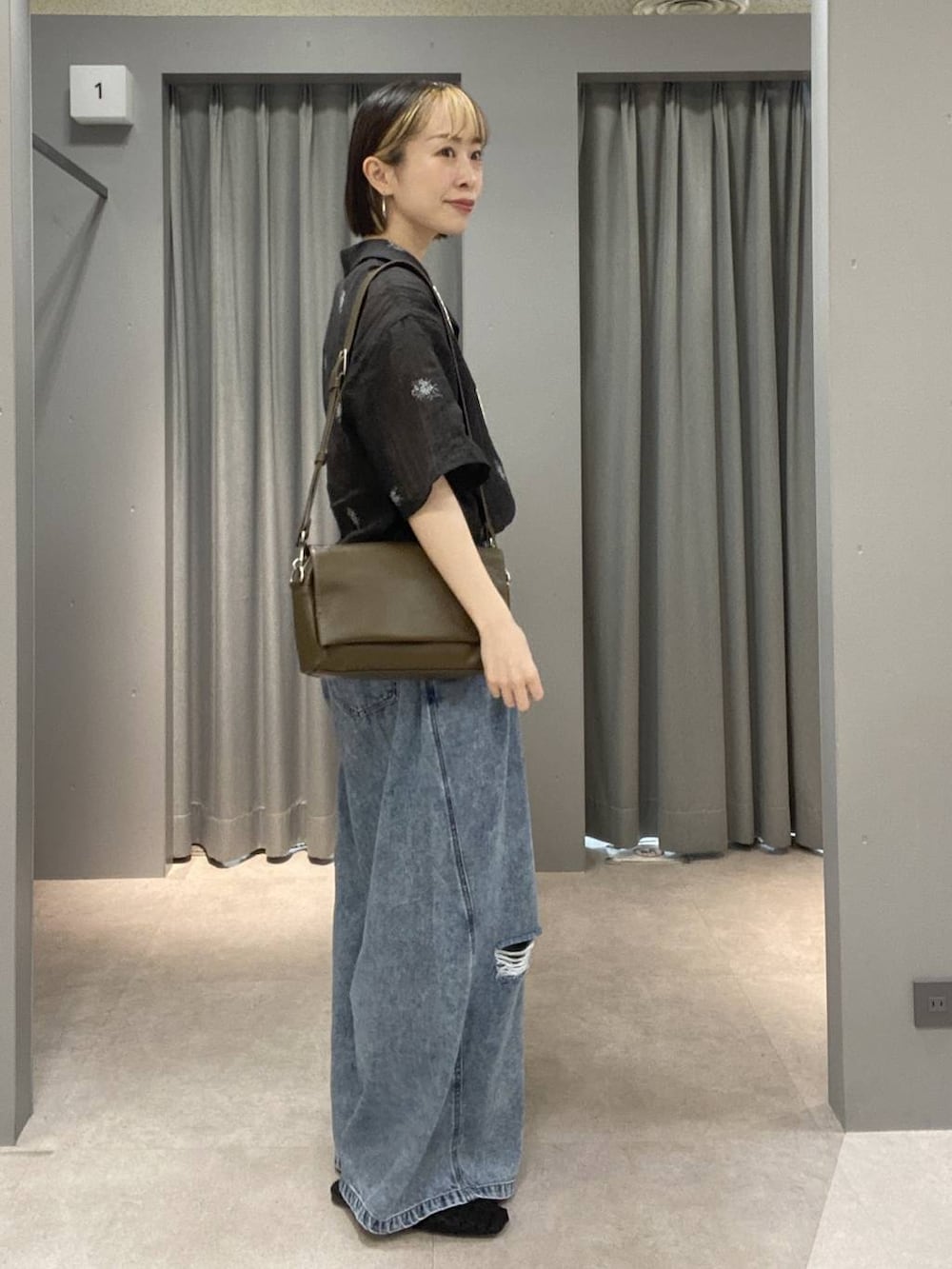 ブラウン系のショルダーバッグ、ブルー系のデニムパンツ、ブラック系のパンプスを着用したレディースの春コーディネートの2枚目の写真