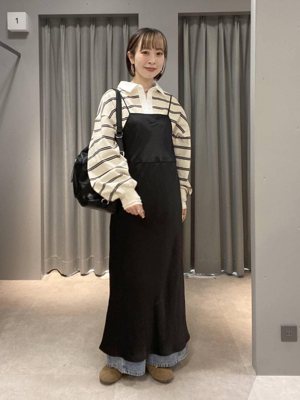 ブラック系のショルダーバッグ、ブルー系のデニムパンツ、ブラウン系のスニーカーを着用したレディースの春コーディネートの4枚目の写真