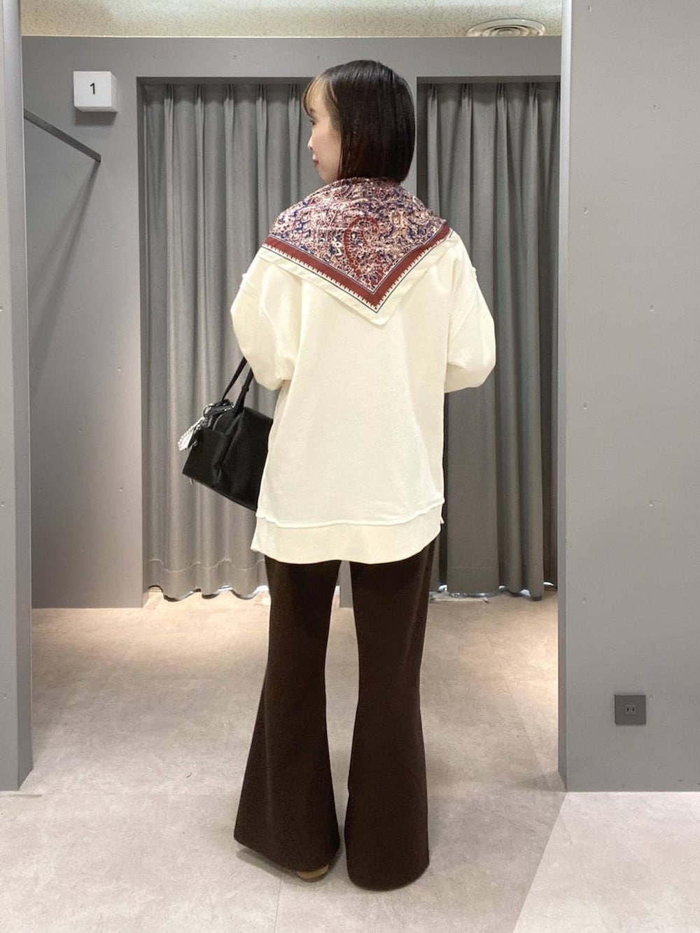 ブラウン系のスニーカー、ブラック系のボストンバッグ、ホワイト系のスウェットを着用したレディースの春コーディネートの3枚目の写真